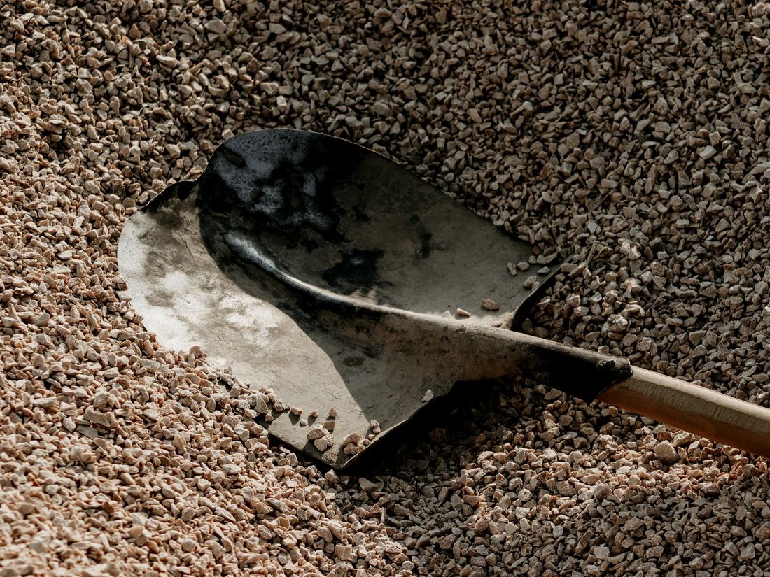 A shovel resting in a pile of gravel