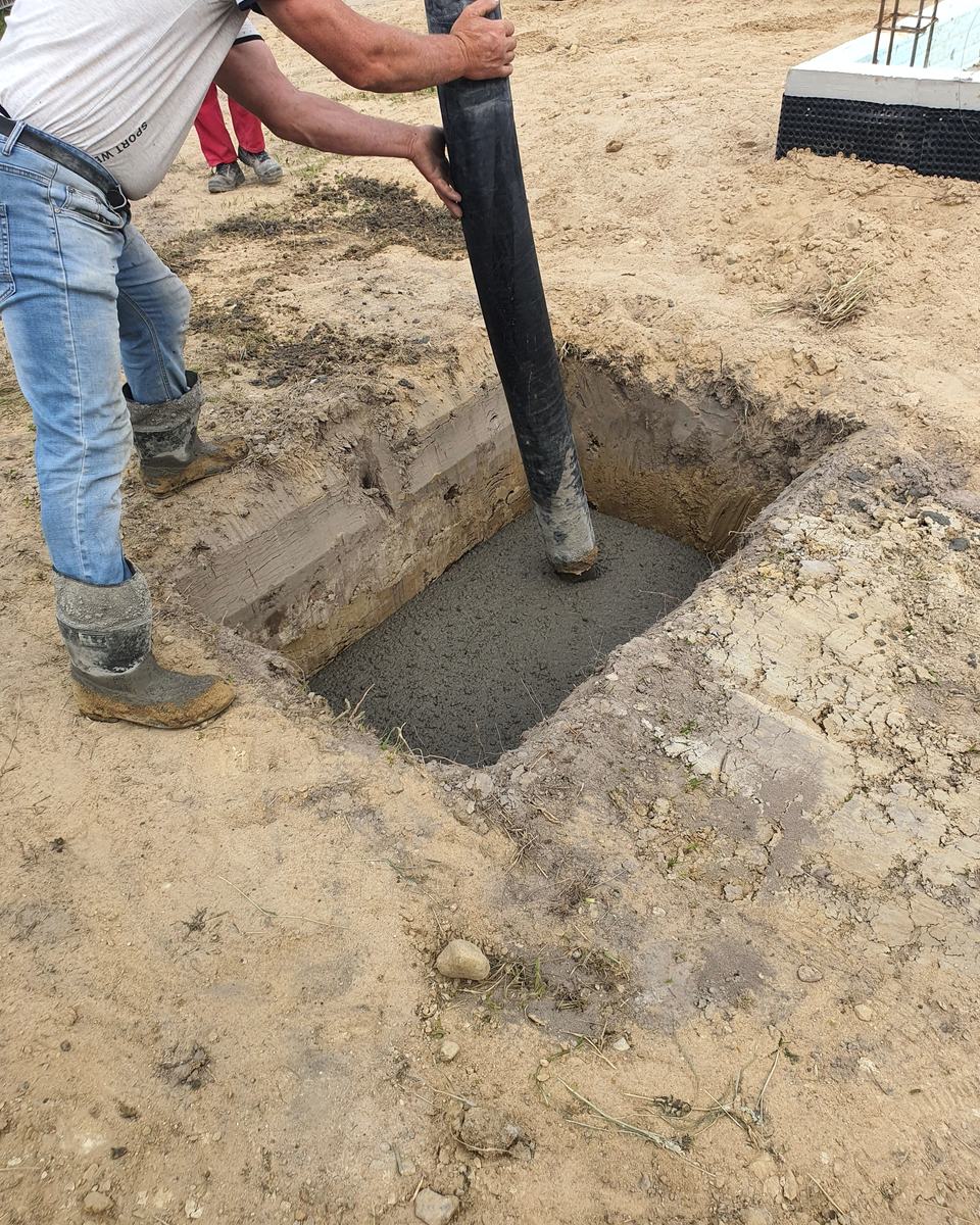 Concrete being poured through a chute into a square foundation