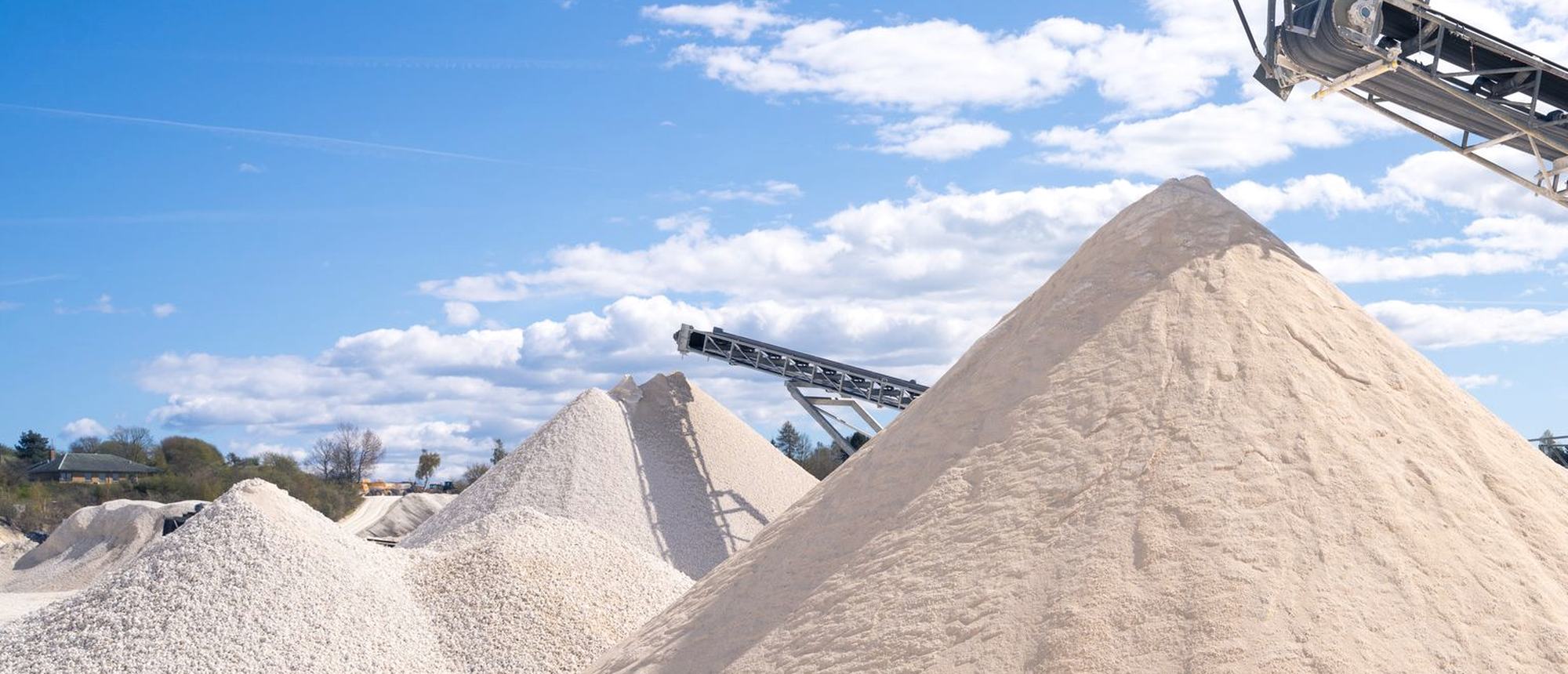Stockpiles of sand and gravel under a conveyor at a quarry